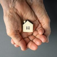 Inheritance,Concept.,Elderly,Woman,Hands,Holds,A,Little,Toy,House.